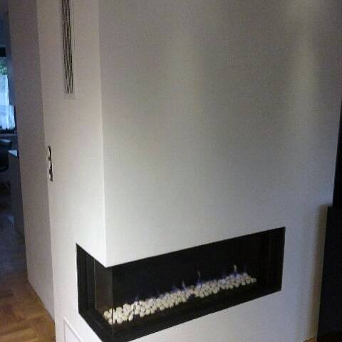 Modern minimalistic corner fireplace design with white stones